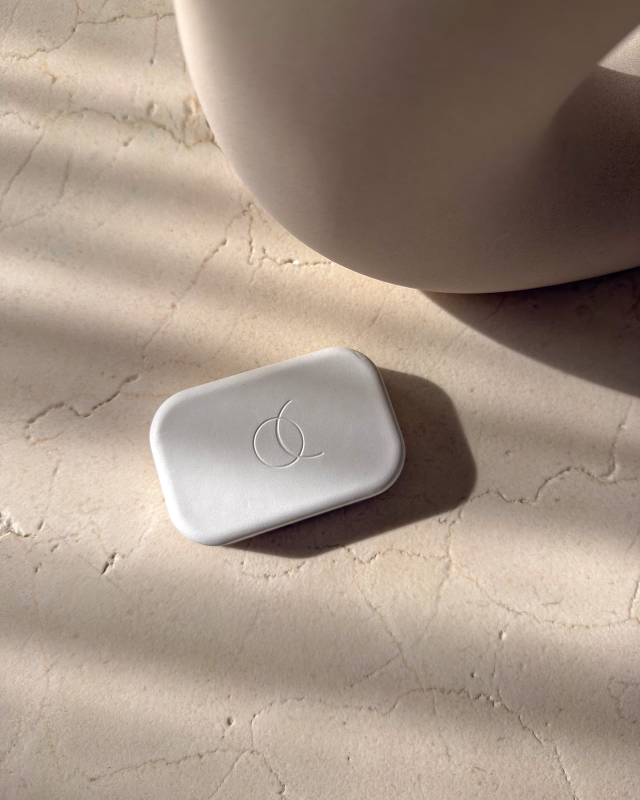 Small white Arc Pulse box with an embossed logo on a stone surface - Luxe Digital