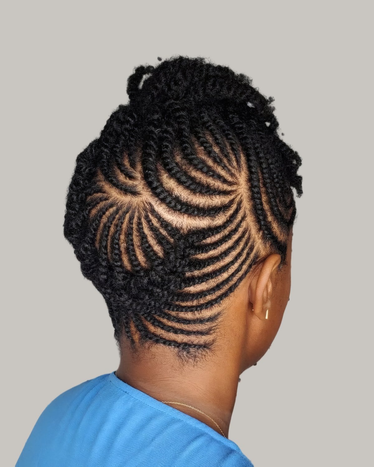 Back view of cornrows curving up from the nape into a braided updo