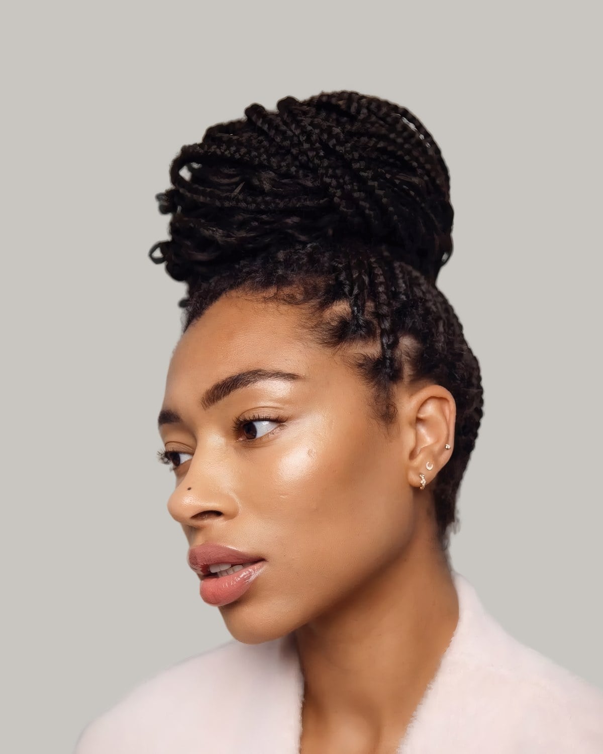 Woman in profile with braids pulled up into a high bun