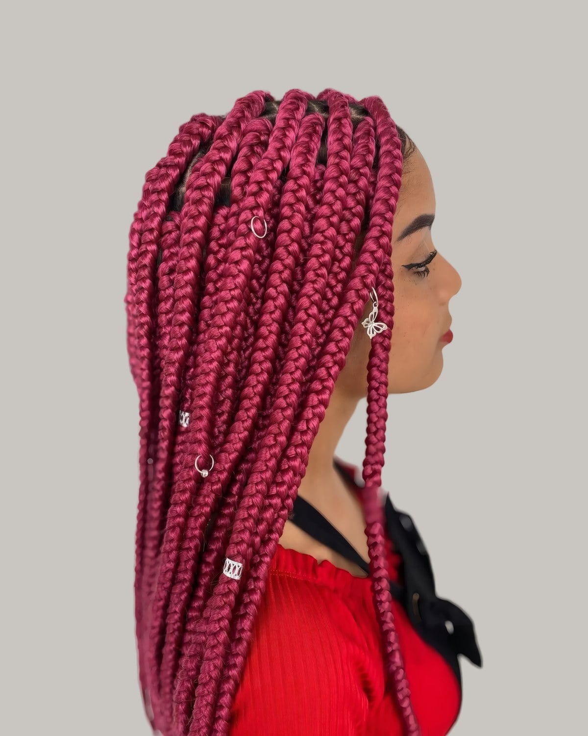 Woman in profile with long burgundy jumbo braids and silver cuffs