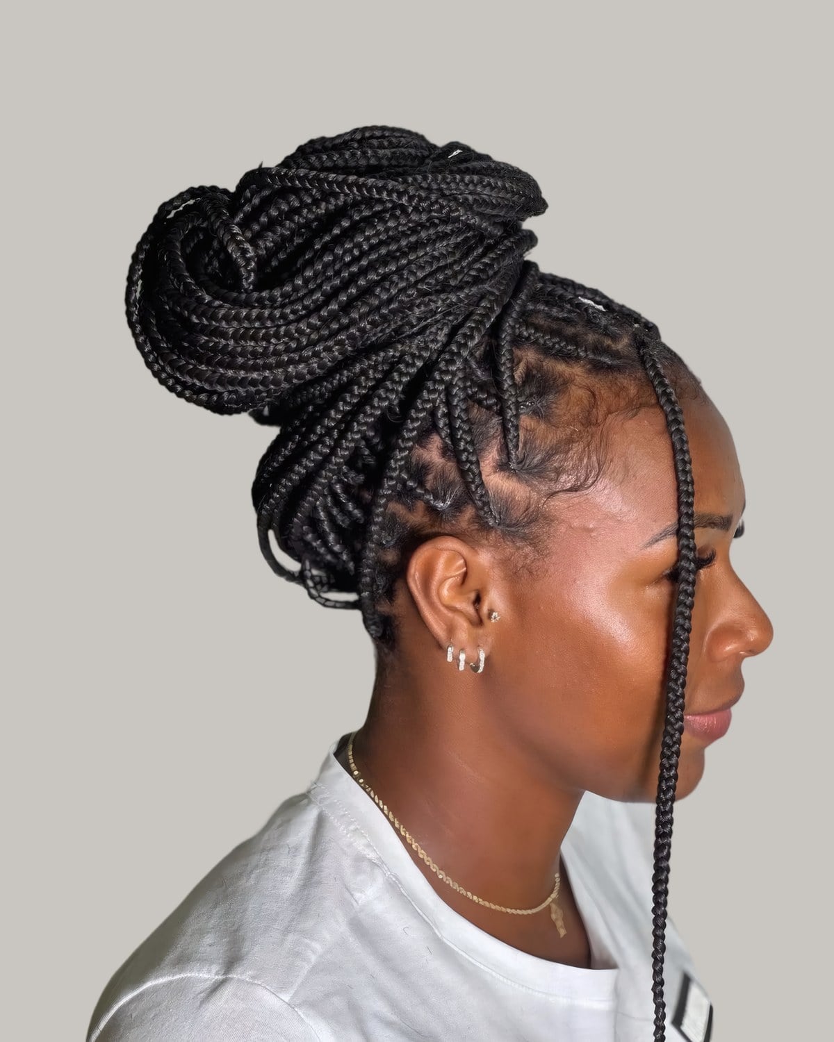 Woman in profile with box braids wound into a high coiled bun