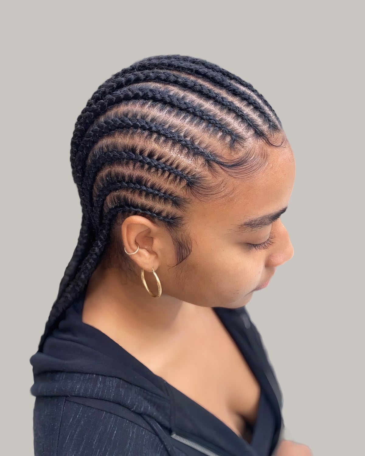 Woman looking down with straight-back cornrows into long braids