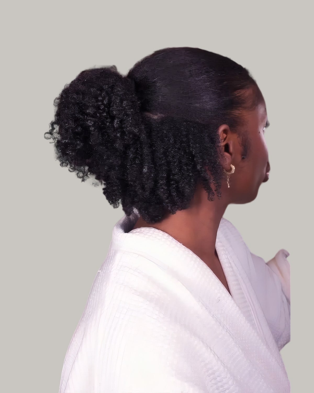 Woman seen from behind with coily hair half up in a bun