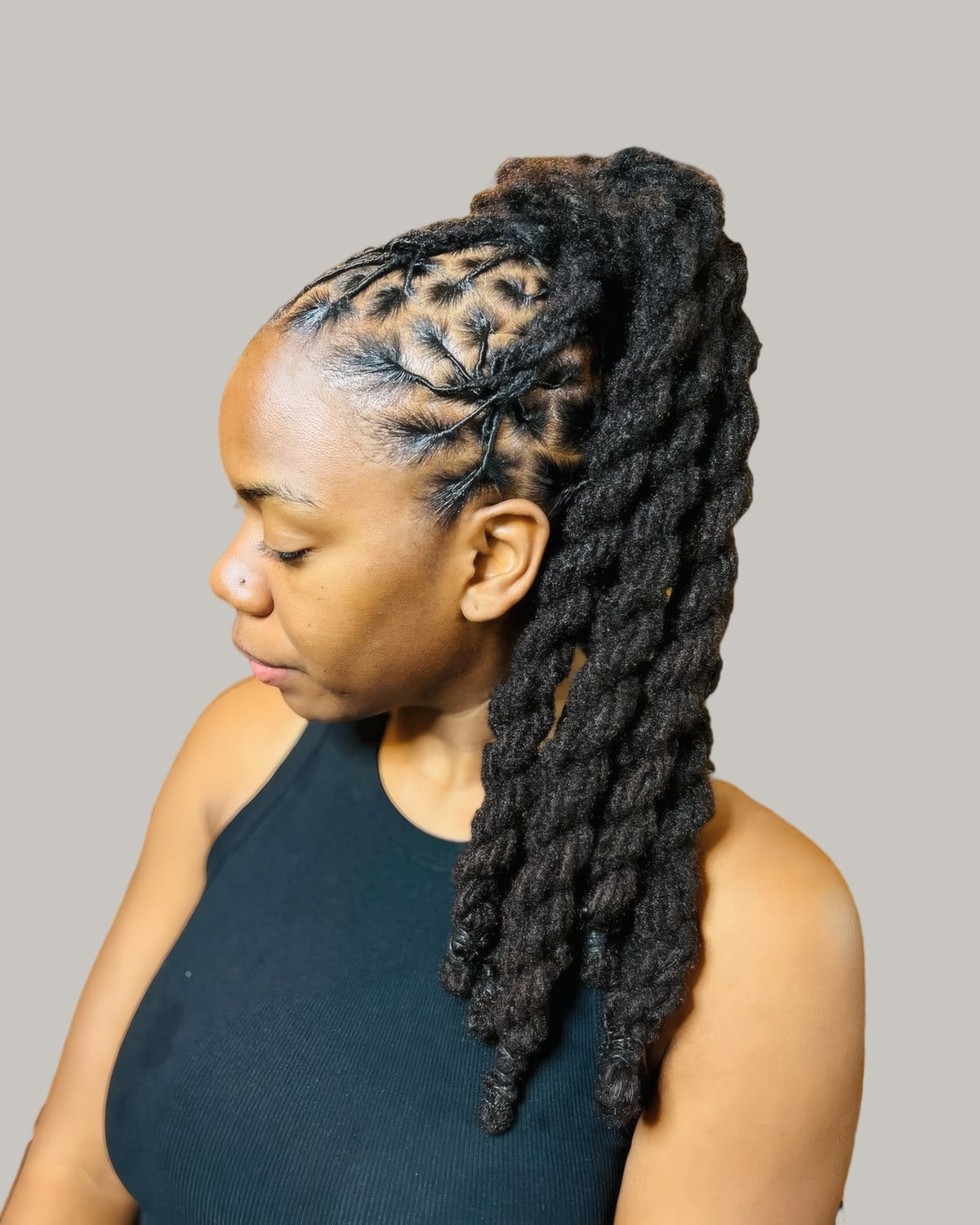 Woman in profile with locs in a high twisted ponytail