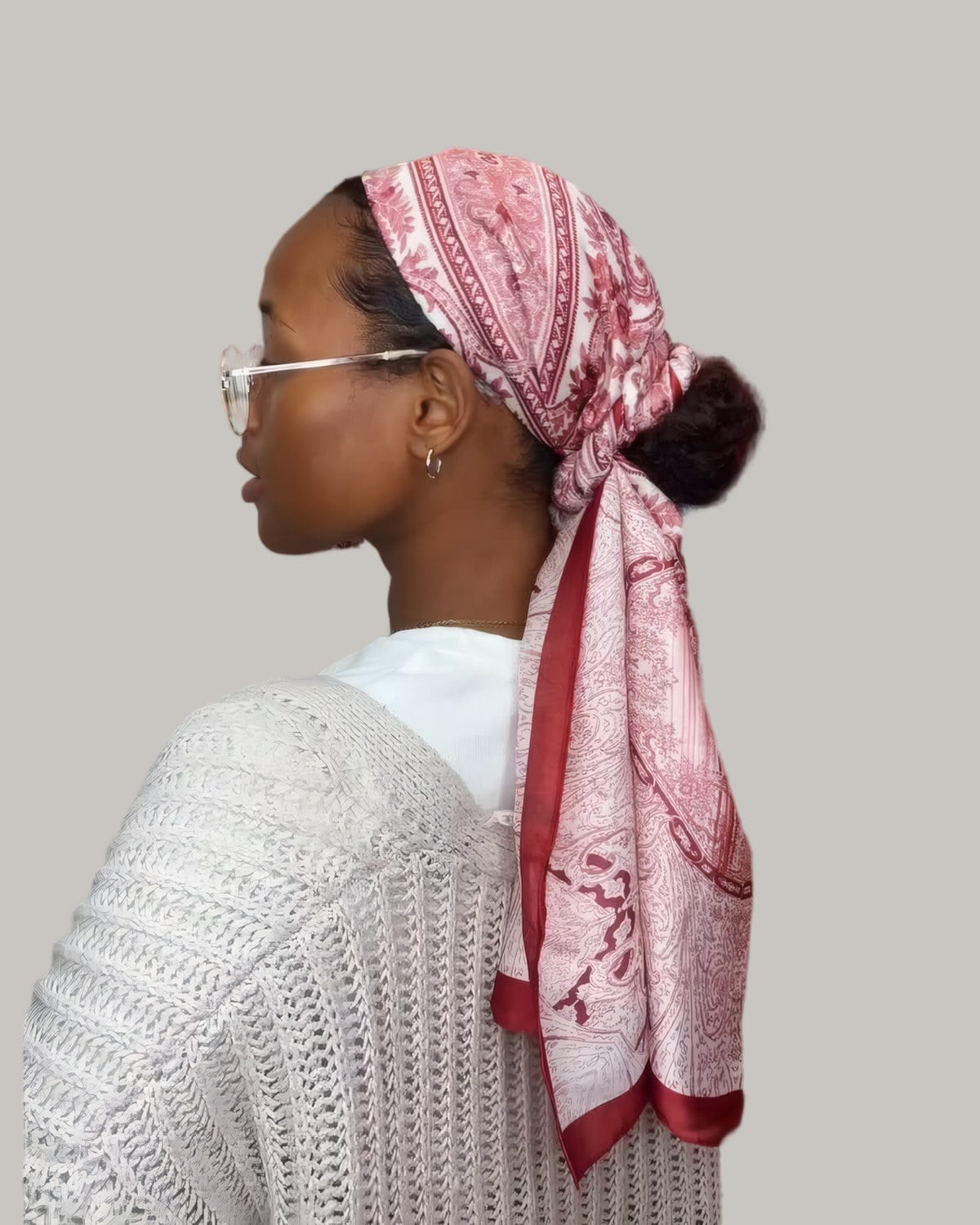 Woman in profile wearing a red and white silk scarf tied at the nape