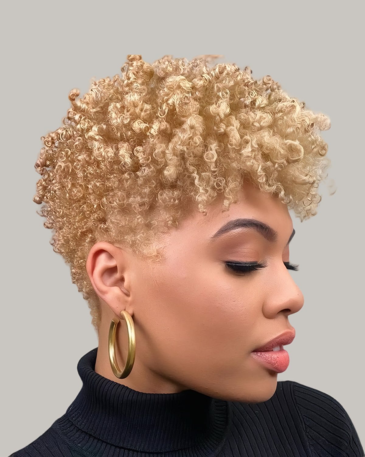 Woman in a black turtleneck with a short honey blonde afro