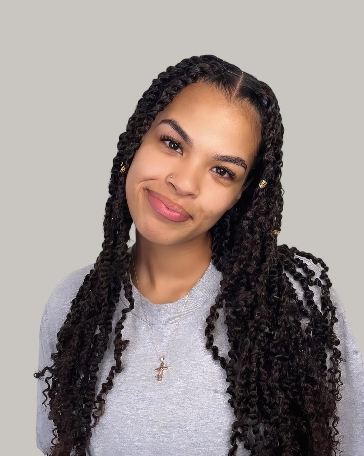 Smiling woman in a grey top with long passion twists