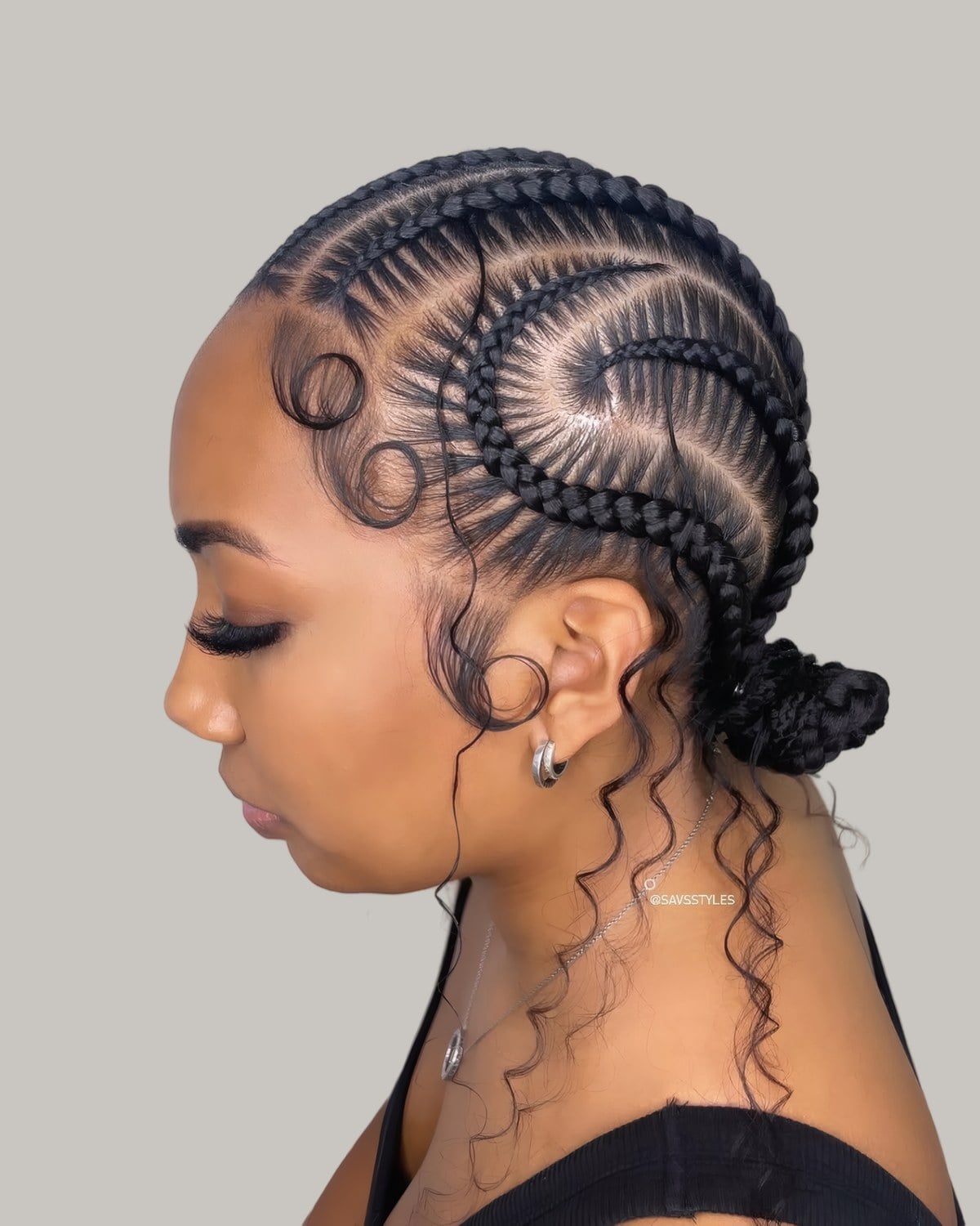 Woman in profile with cornrows curving into a low braided bun