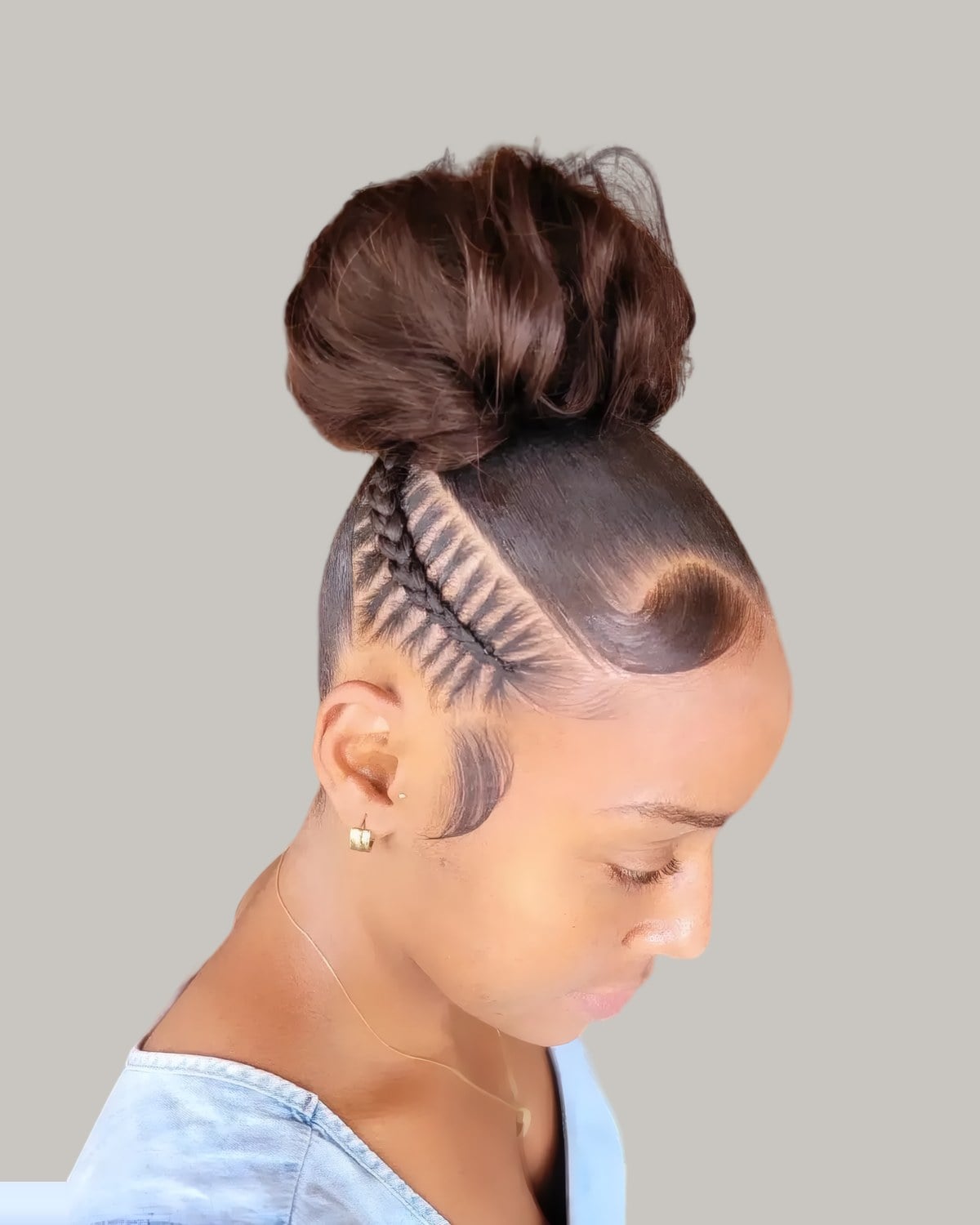 Woman looking down with a high bun and braided sides