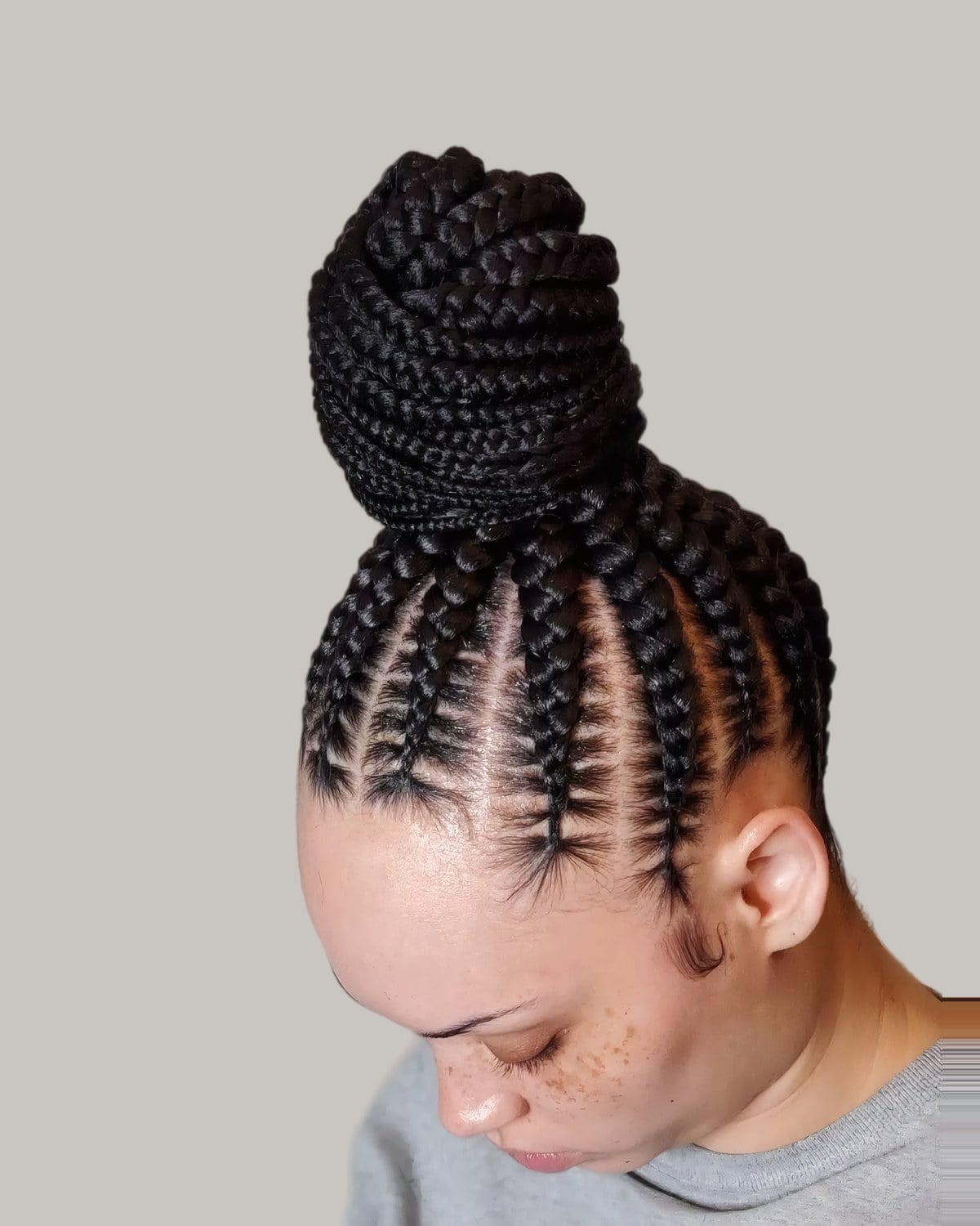 Woman looking down with cornrows braided up into a large top knot