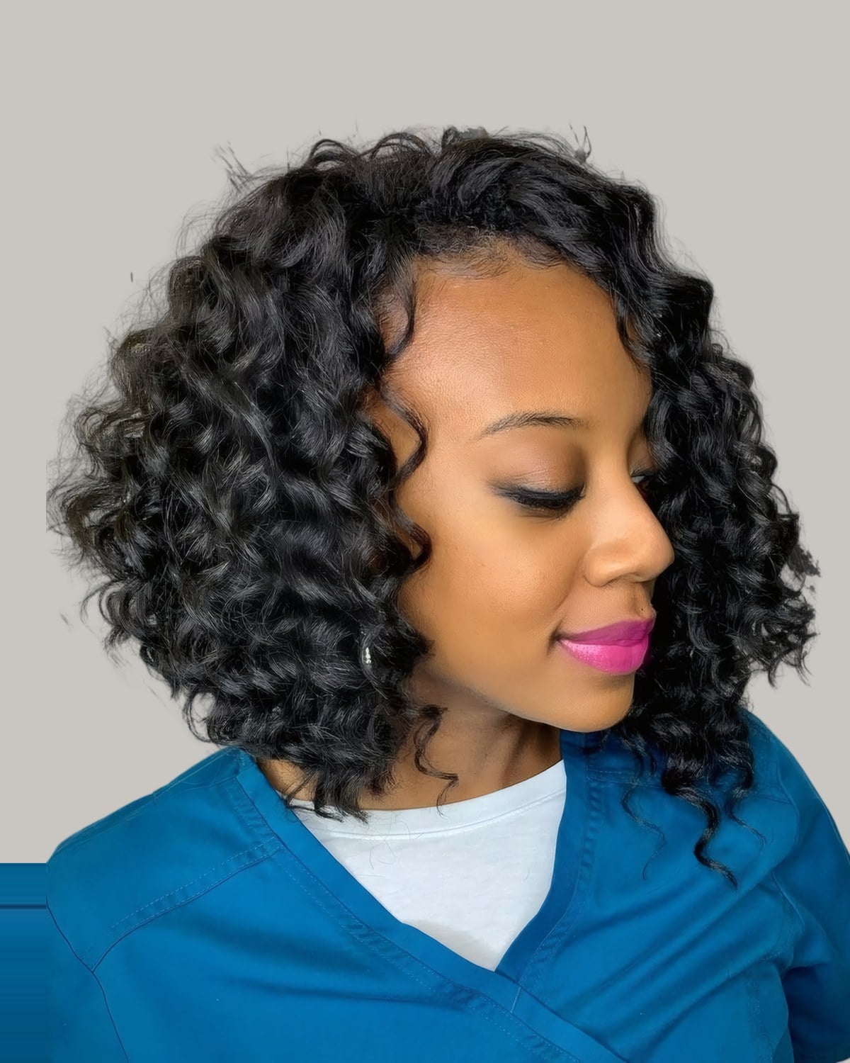 Woman in blue scrubs with a side-parted curly bob