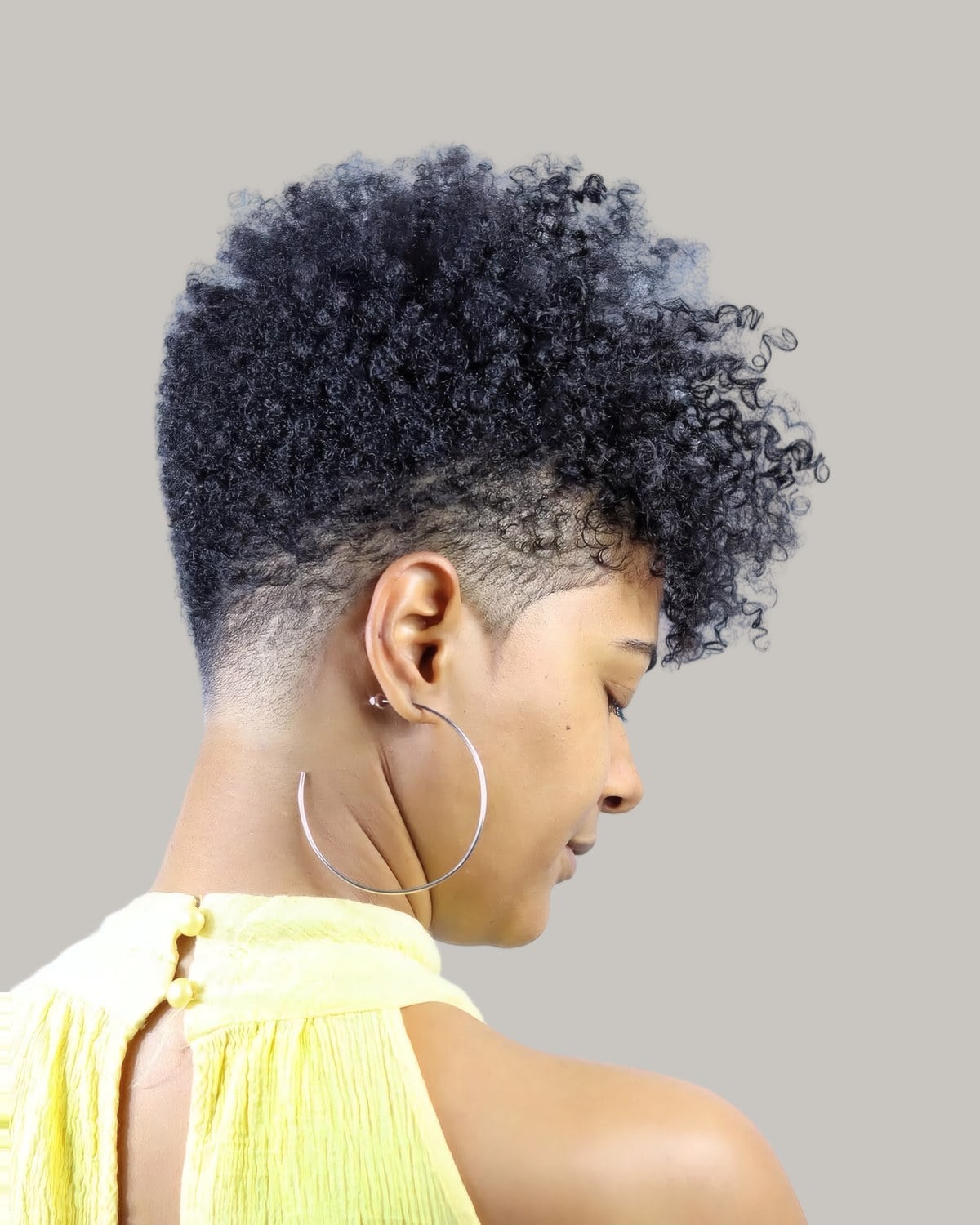 Woman seen from the side with a short curly afro tapered at the nape