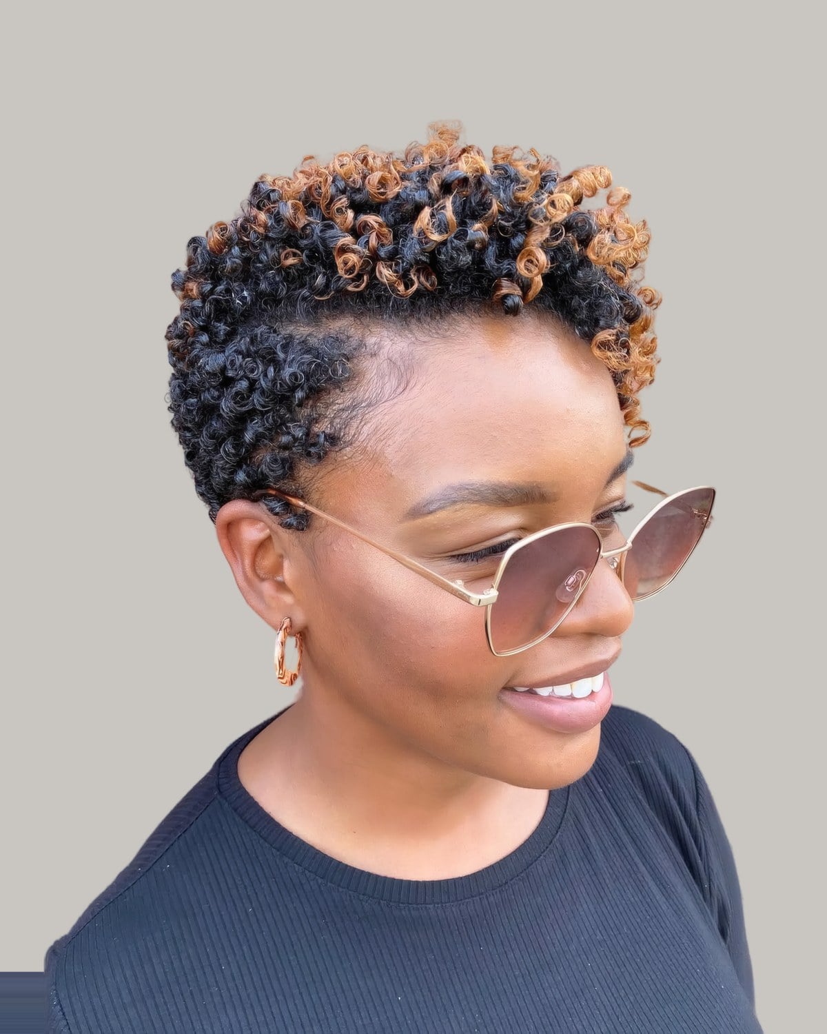 Smiling woman in sunglasses with a short curly wash-n-go