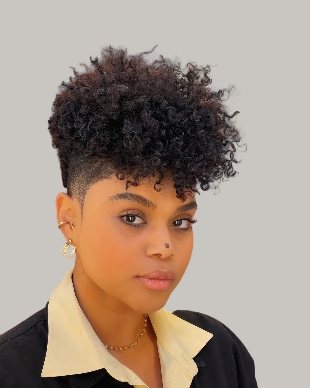 Woman with a curly tapered cut, longer on top