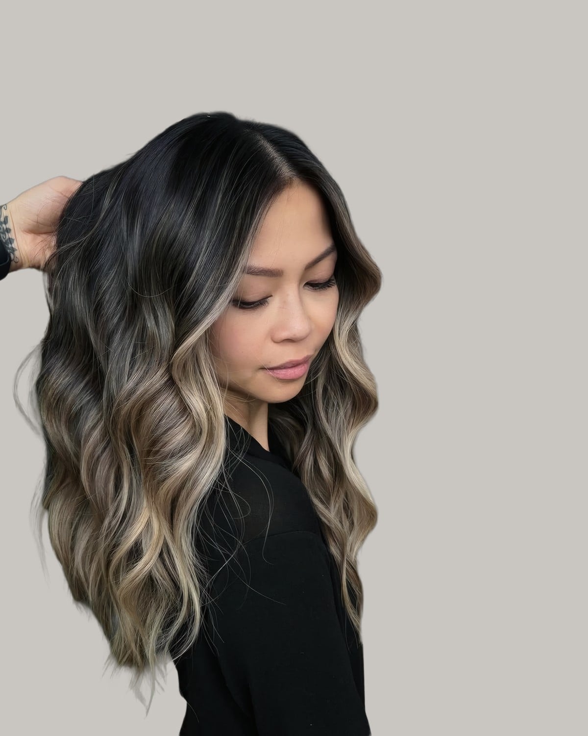 Woman in profile looking down with a dark root and beige balayage