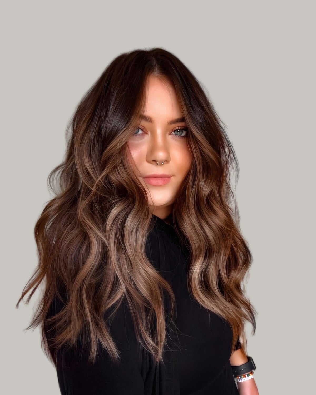 Woman facing the camera with a dark root and long caramel waves