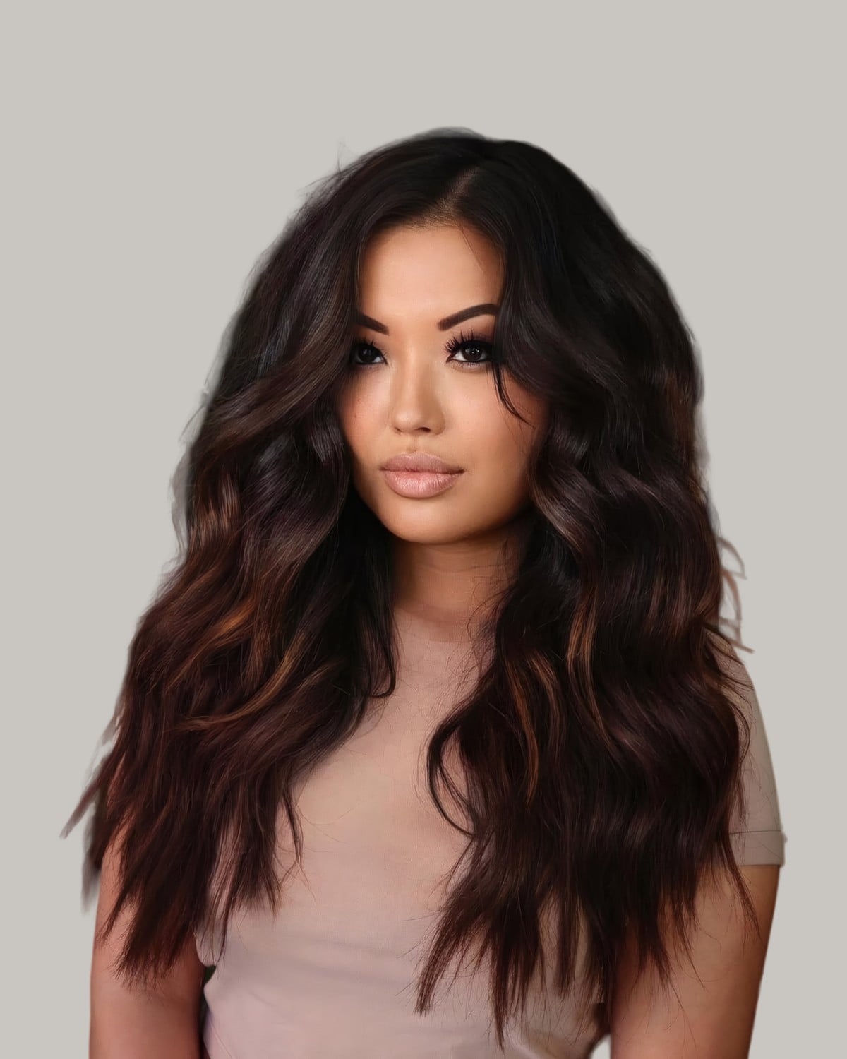 Woman with voluminous black waves and caramel tones on the ends