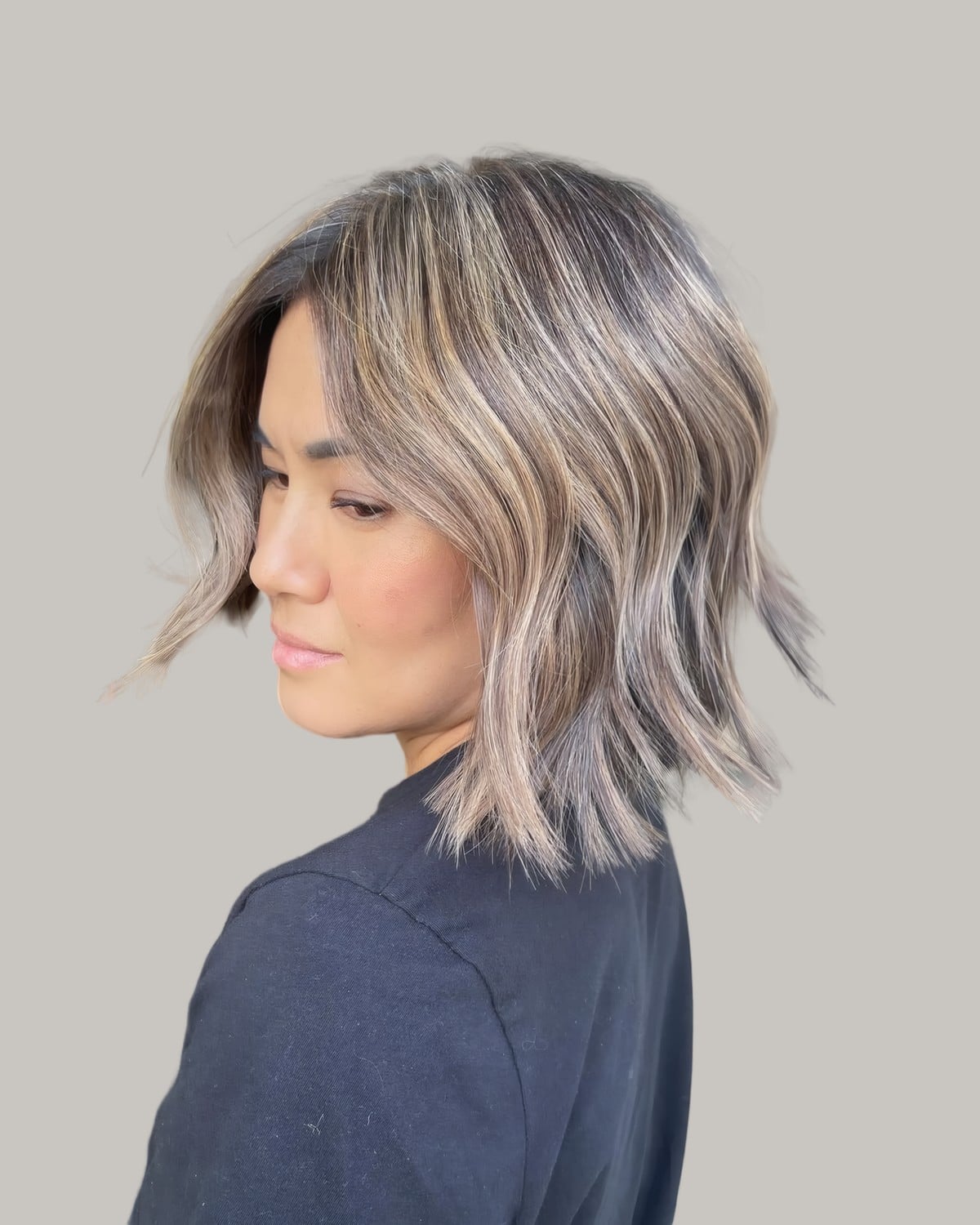 Woman turned to the side with a lob of dark hair and silver beige pieces
