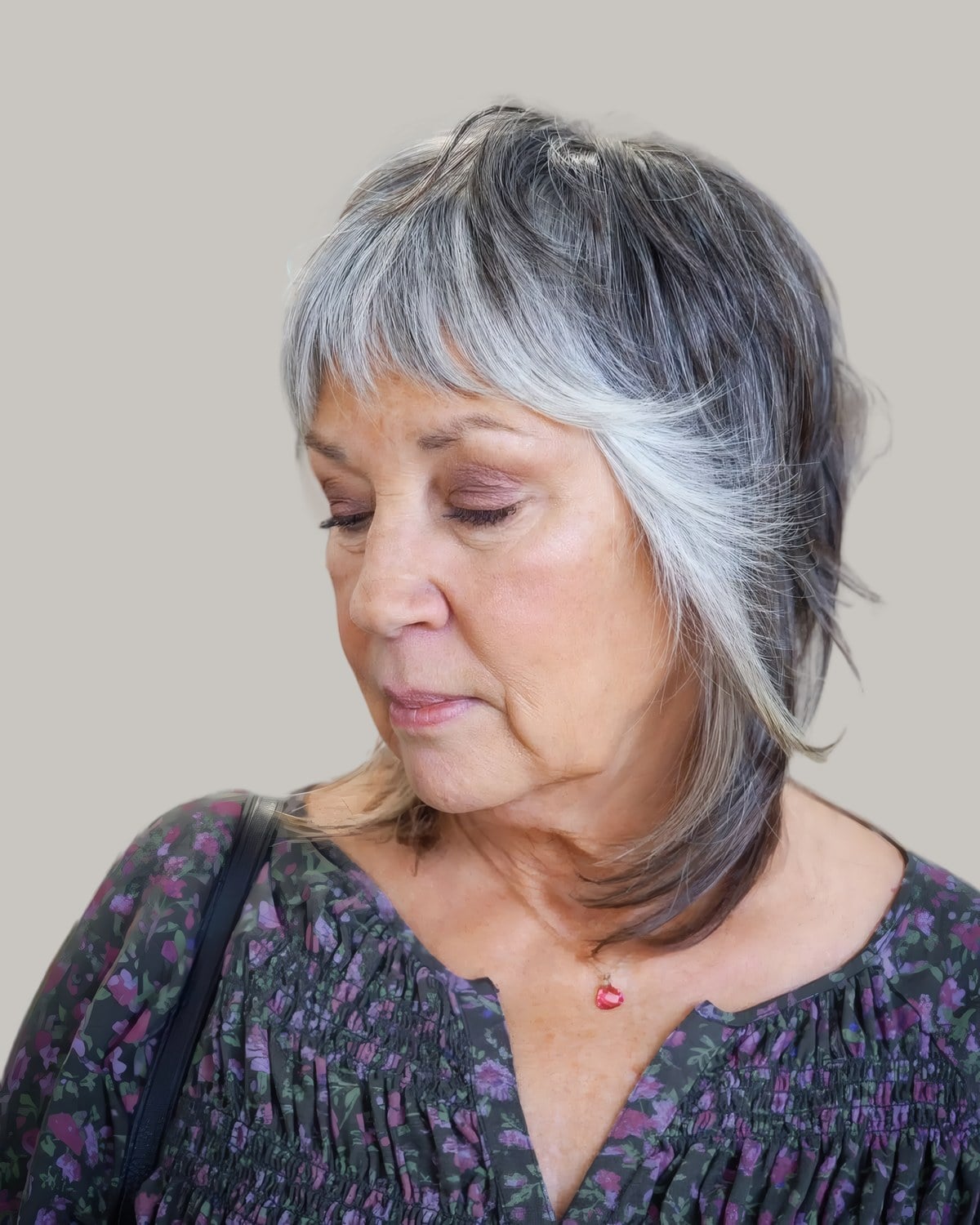 Woman looking down with a layered gray shag and a short fringe
