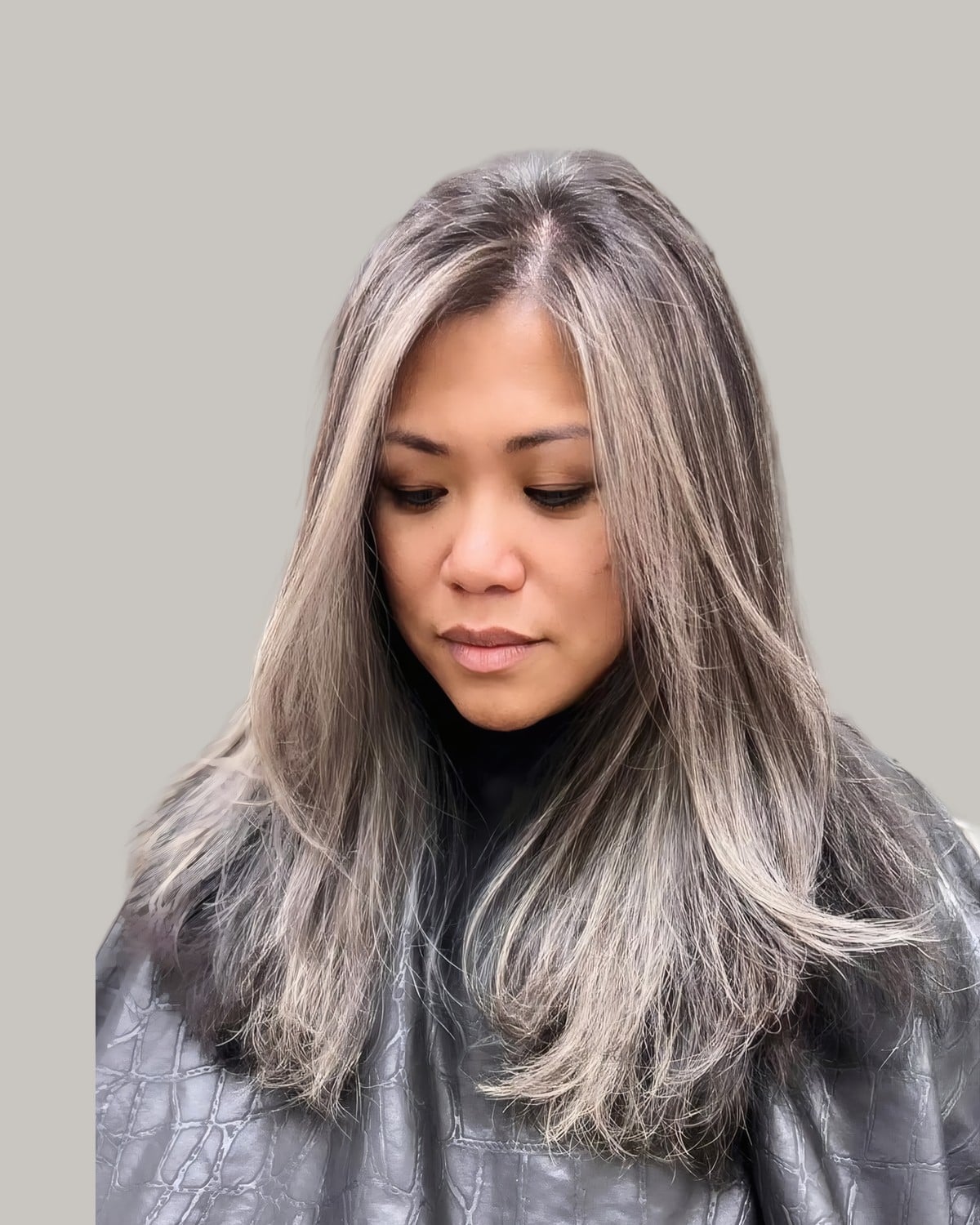 Woman looking down with long silver gray hair and darker lowlights