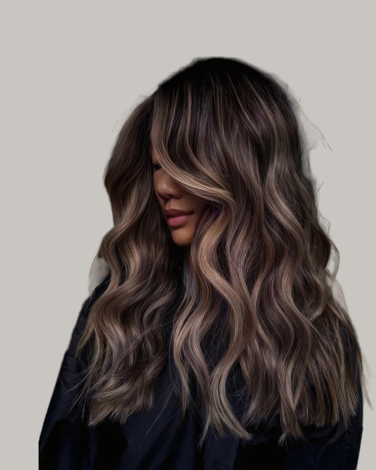Woman looking to the side with dark hair and light brown balayage