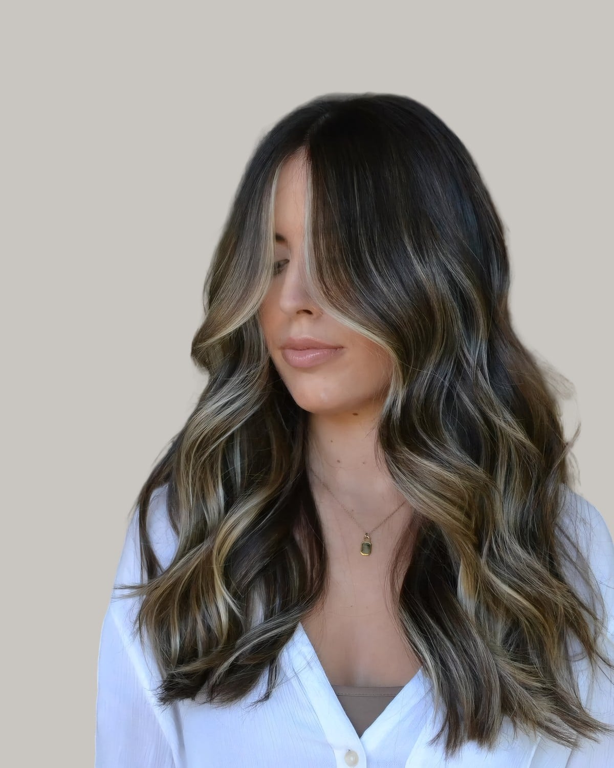Woman in a white shirt with long dark hair and cool mushroom brown highlights