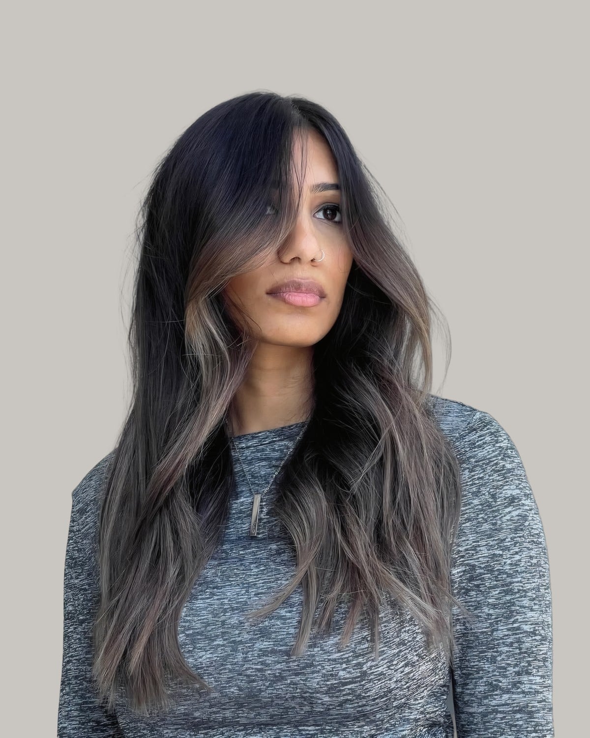 Woman in a gray sweater with long dark hair and soft ash brown face-framing strands