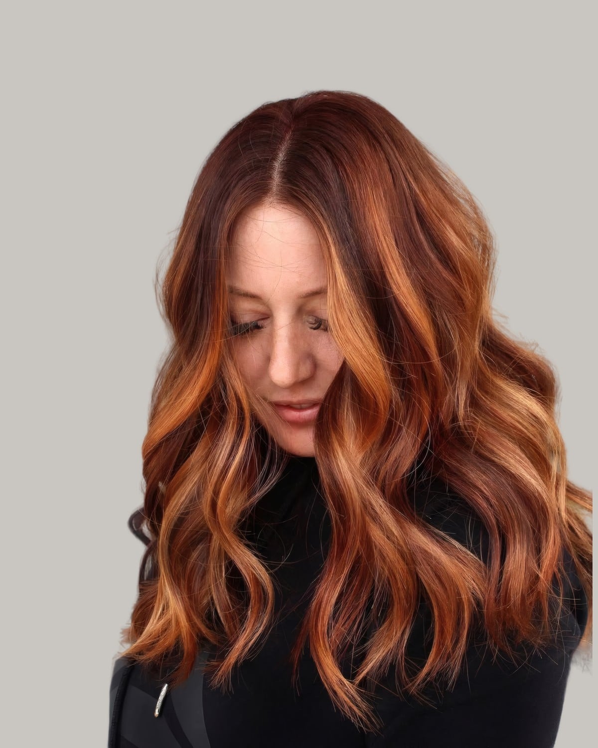Woman looking down with copper-peach waves over a darker root