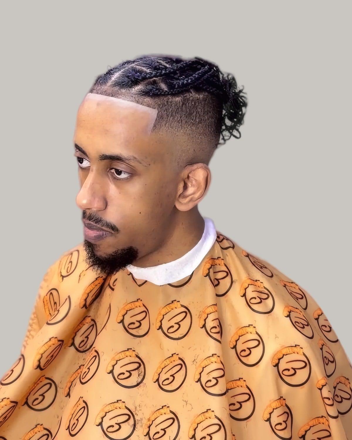 Man with a braided top knot and a taper, seen in profile