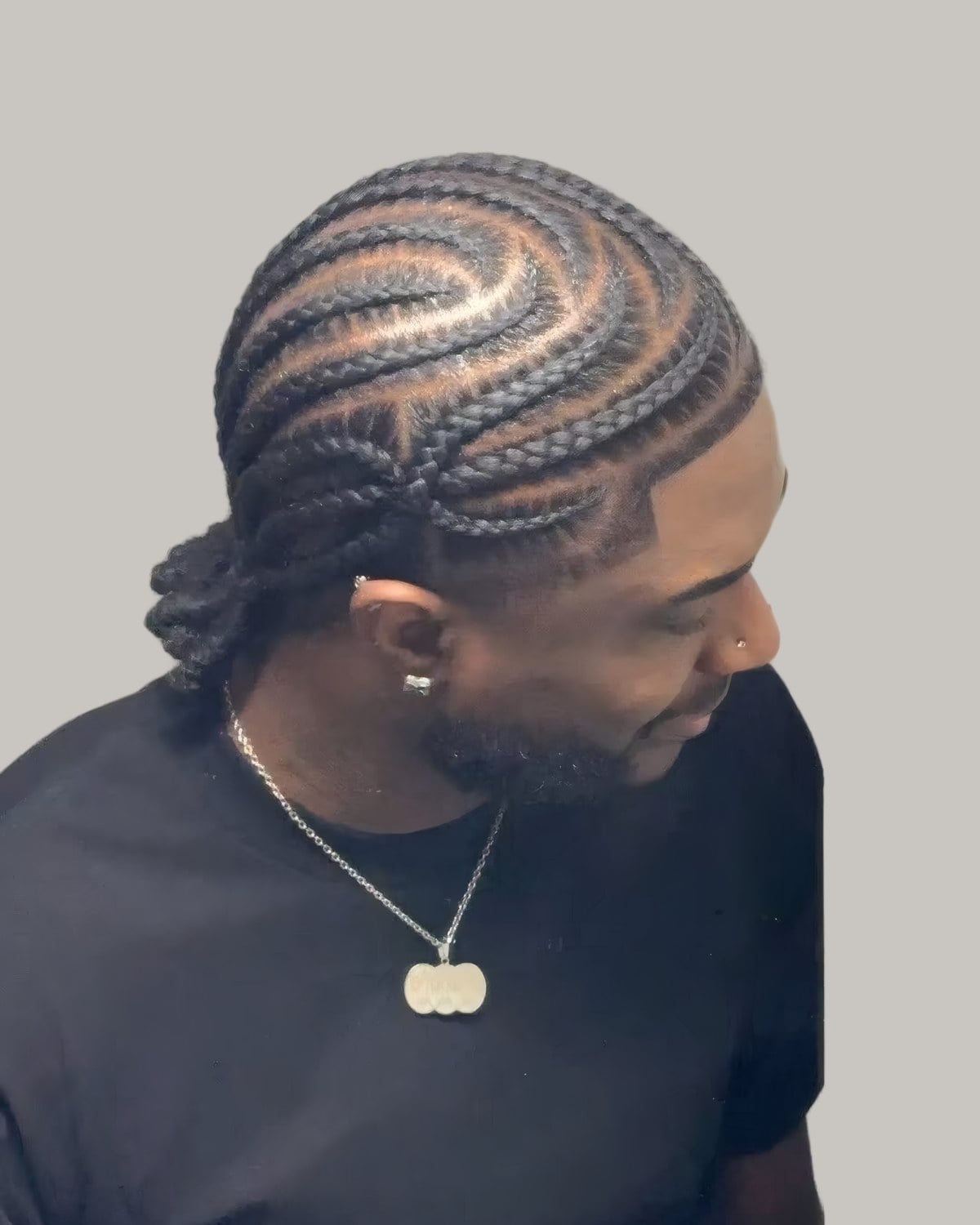 Bearded man with curved cornrows, seen at an angle