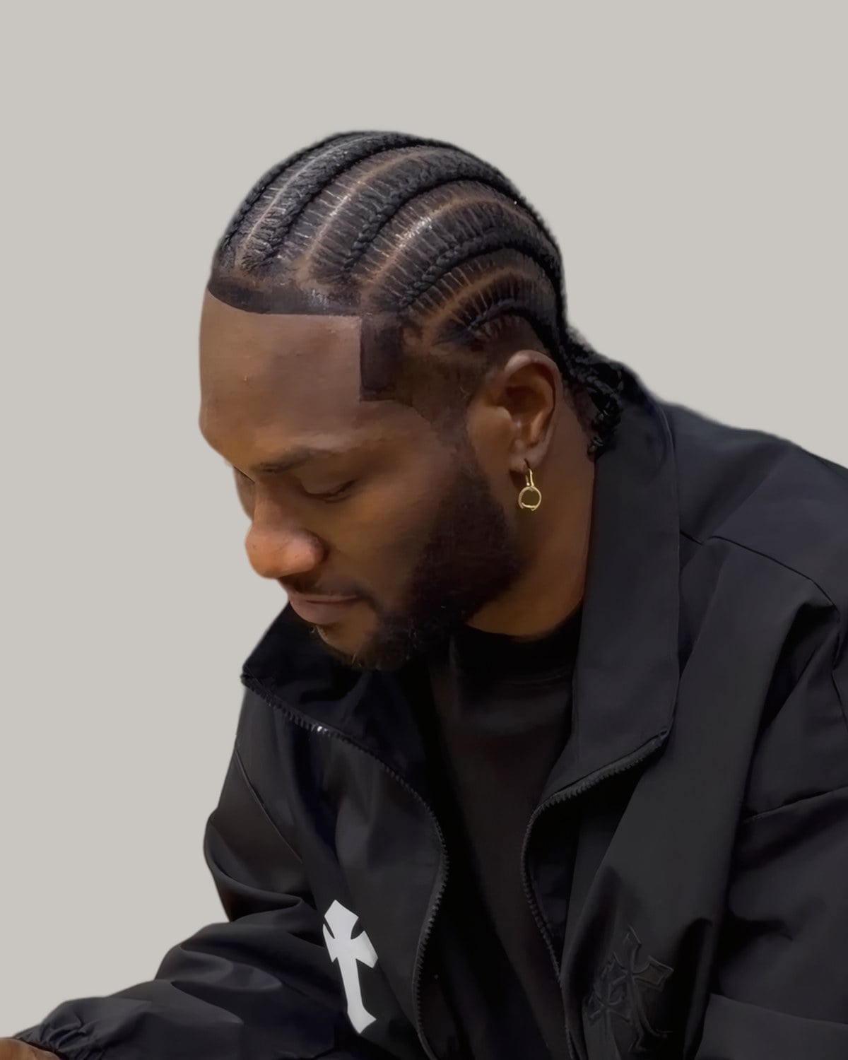 Bearded man with straight cornrows, looking down