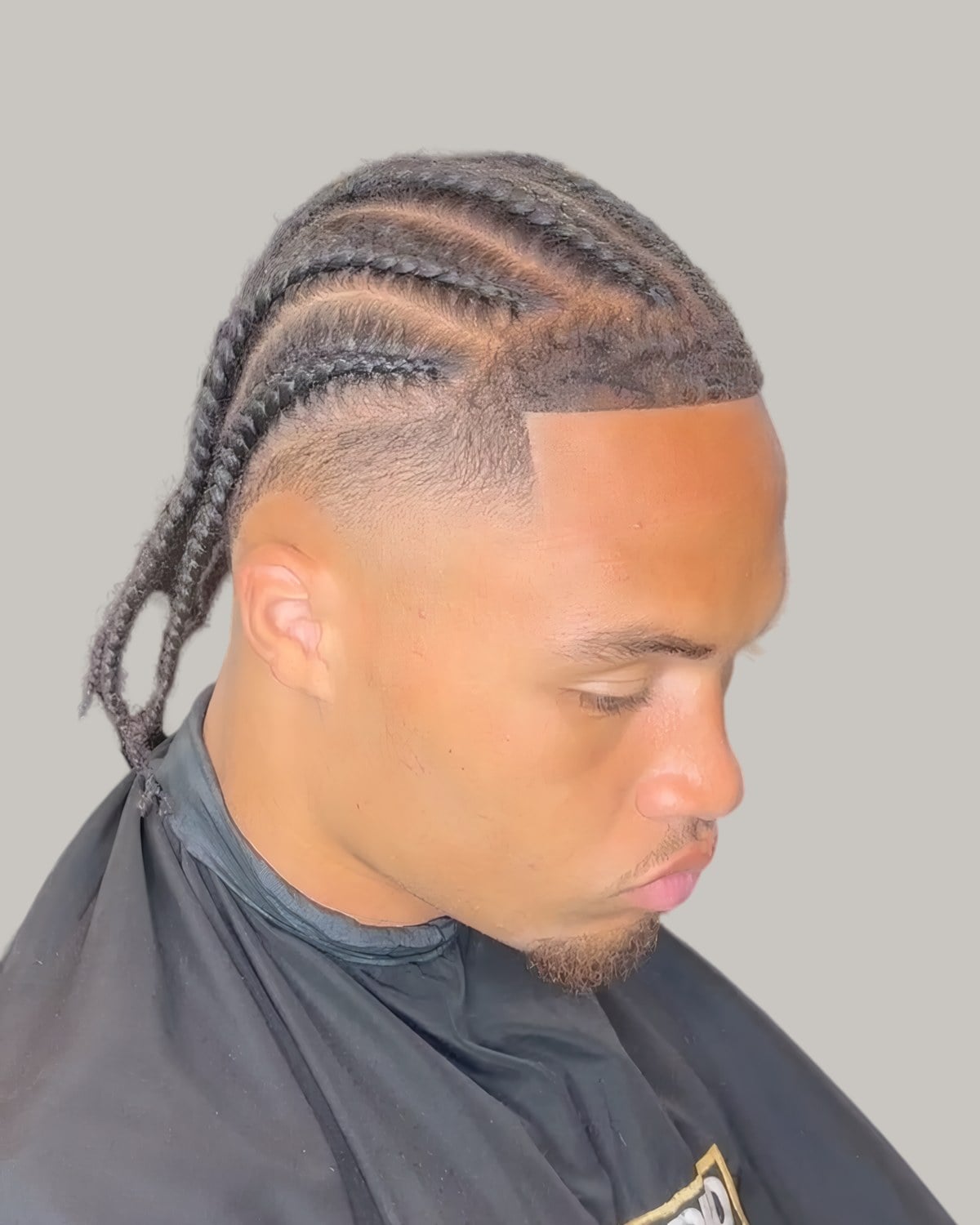 Man with cornrows and a faded side, seen at an angle