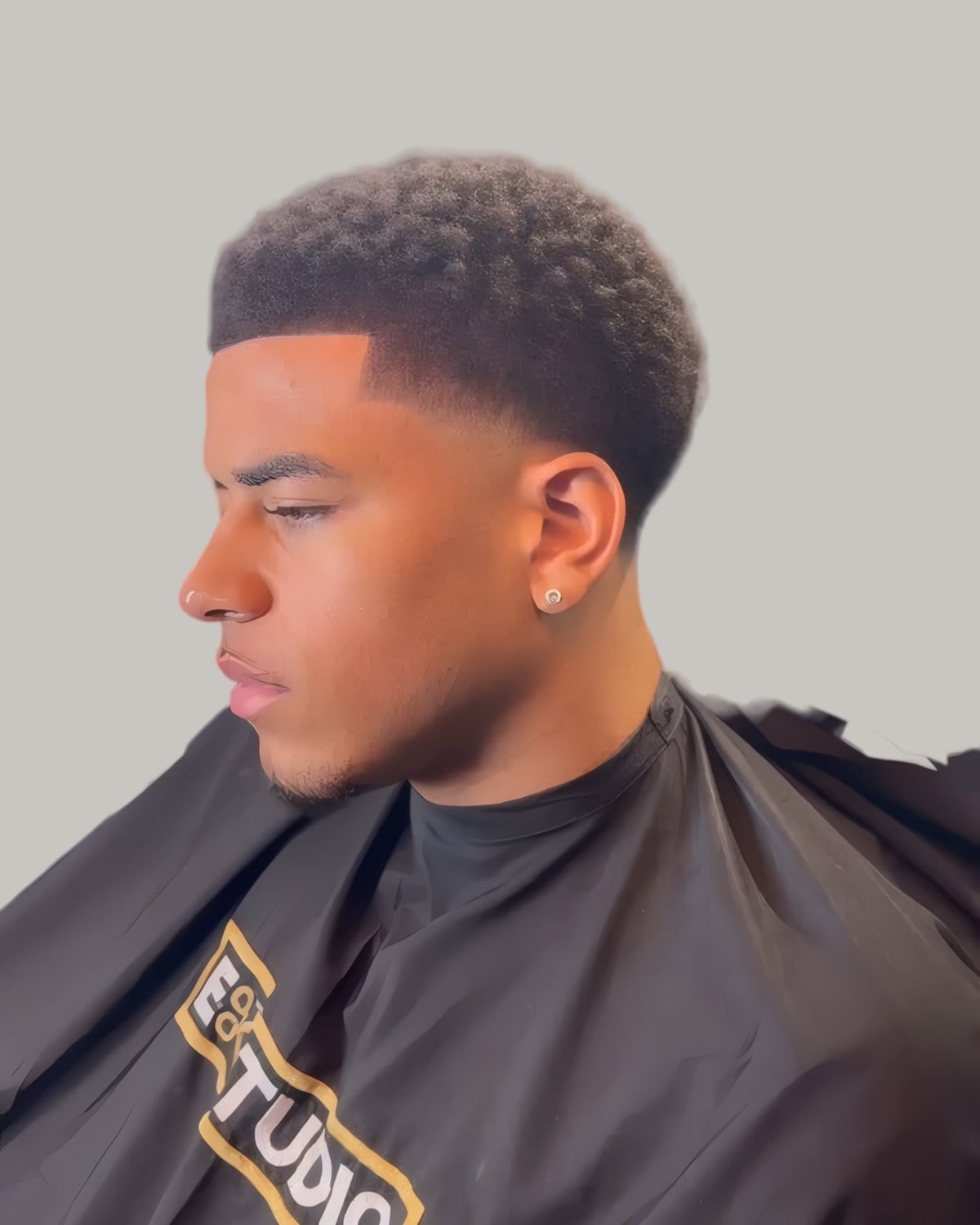 Man with a short curly top and a taper, seen in profile