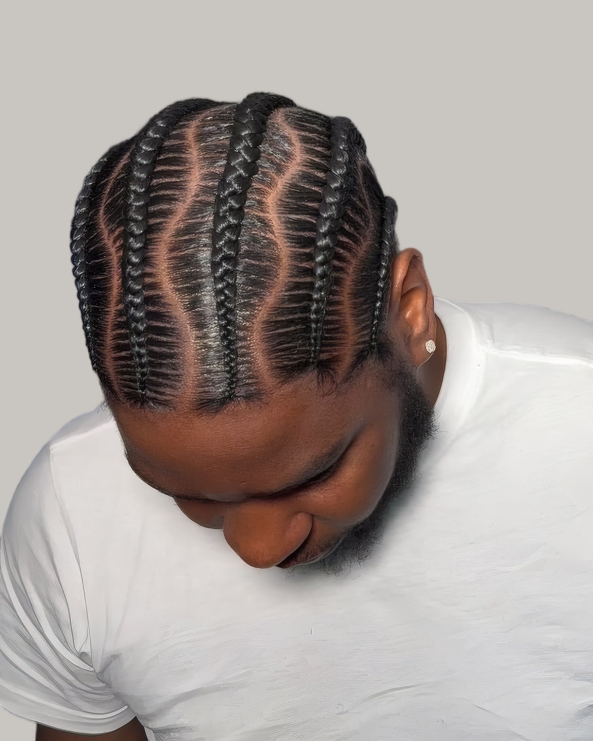 Bearded man with wavy cornrows, looking down