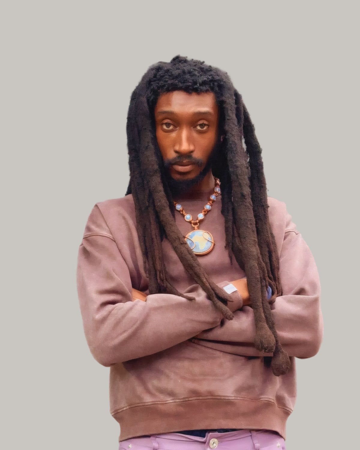 Bearded man with long freeform locs, arms crossed