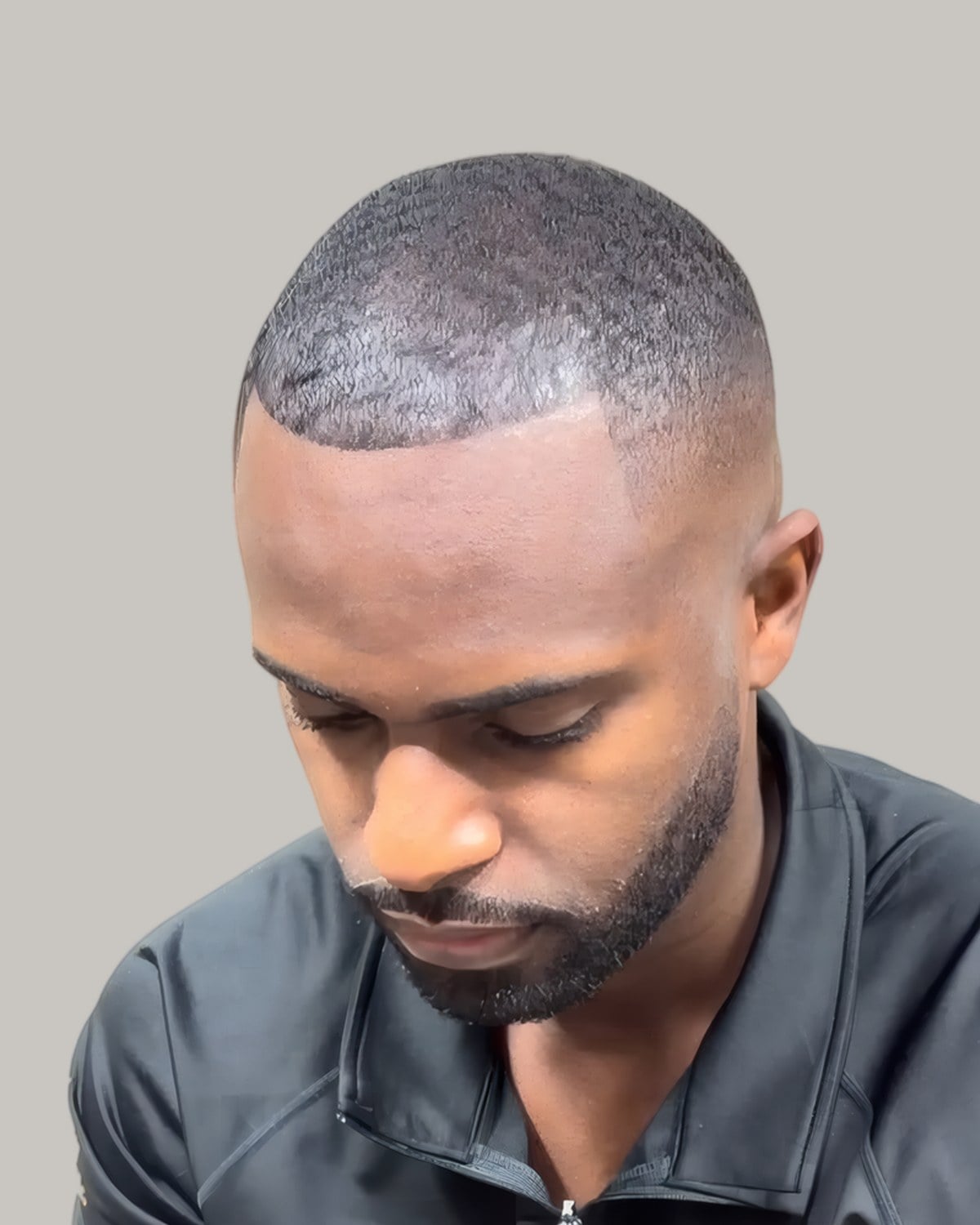 Man with a short low cut and a line-up, looking down