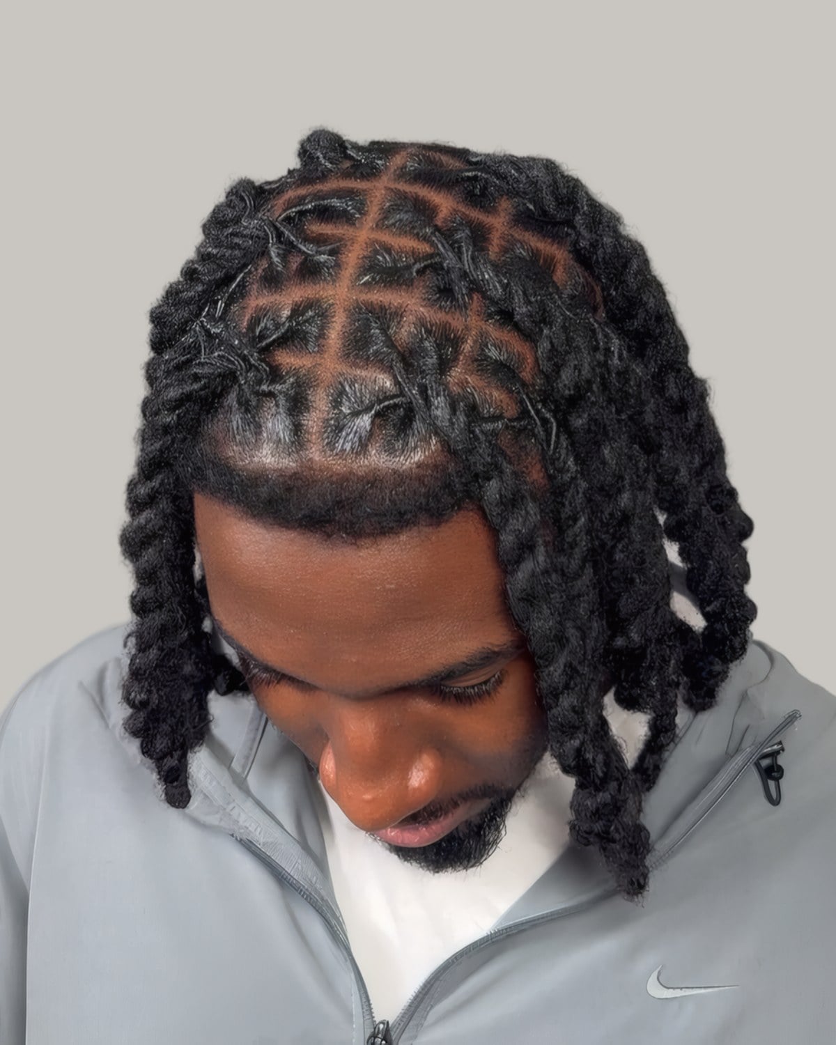 Bearded man with medium two-strand twists, looking down