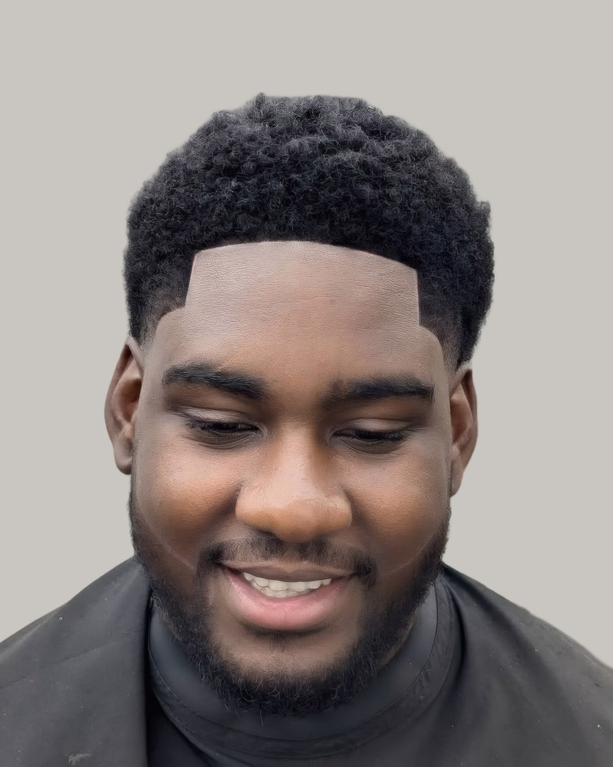 Smiling man with a short afro and a line-up, seen from the front