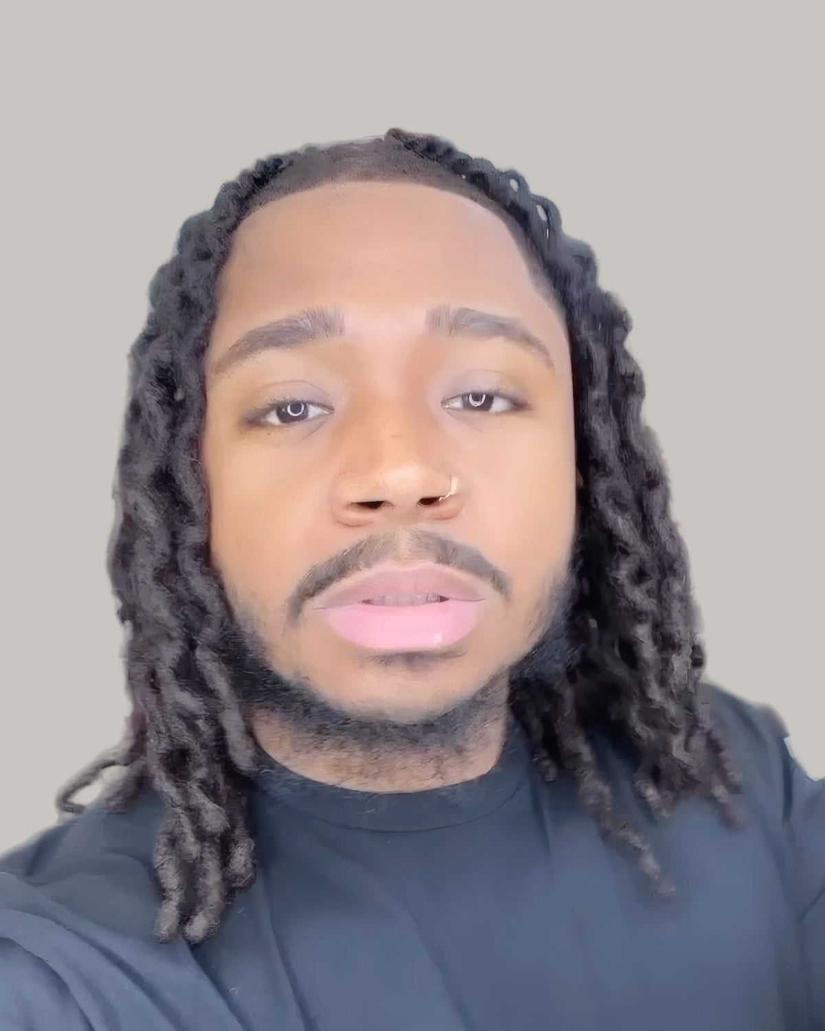 Man with locs falling to the collarbone, seen from the front