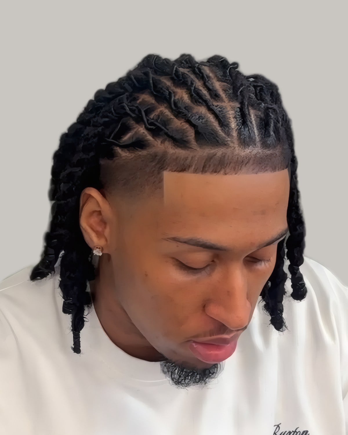 Man with twists on top and faded sides, looking down
