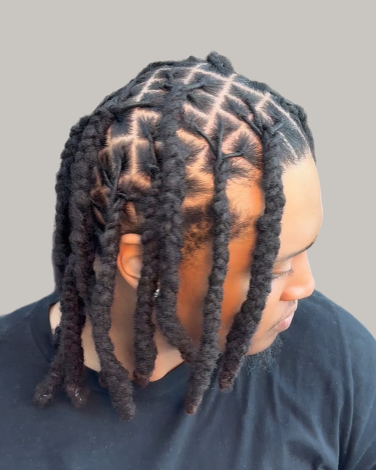 Man with two-strand starter locs and square parts, looking down