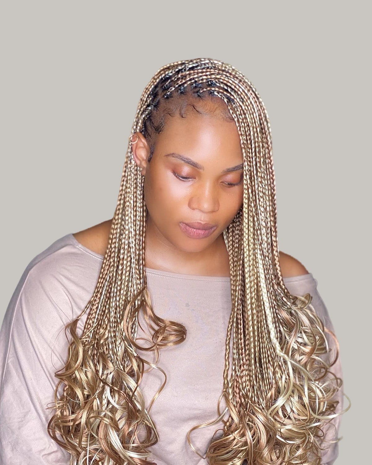 Woman looking down with long honey-blonde French curl braids over her shoulders
