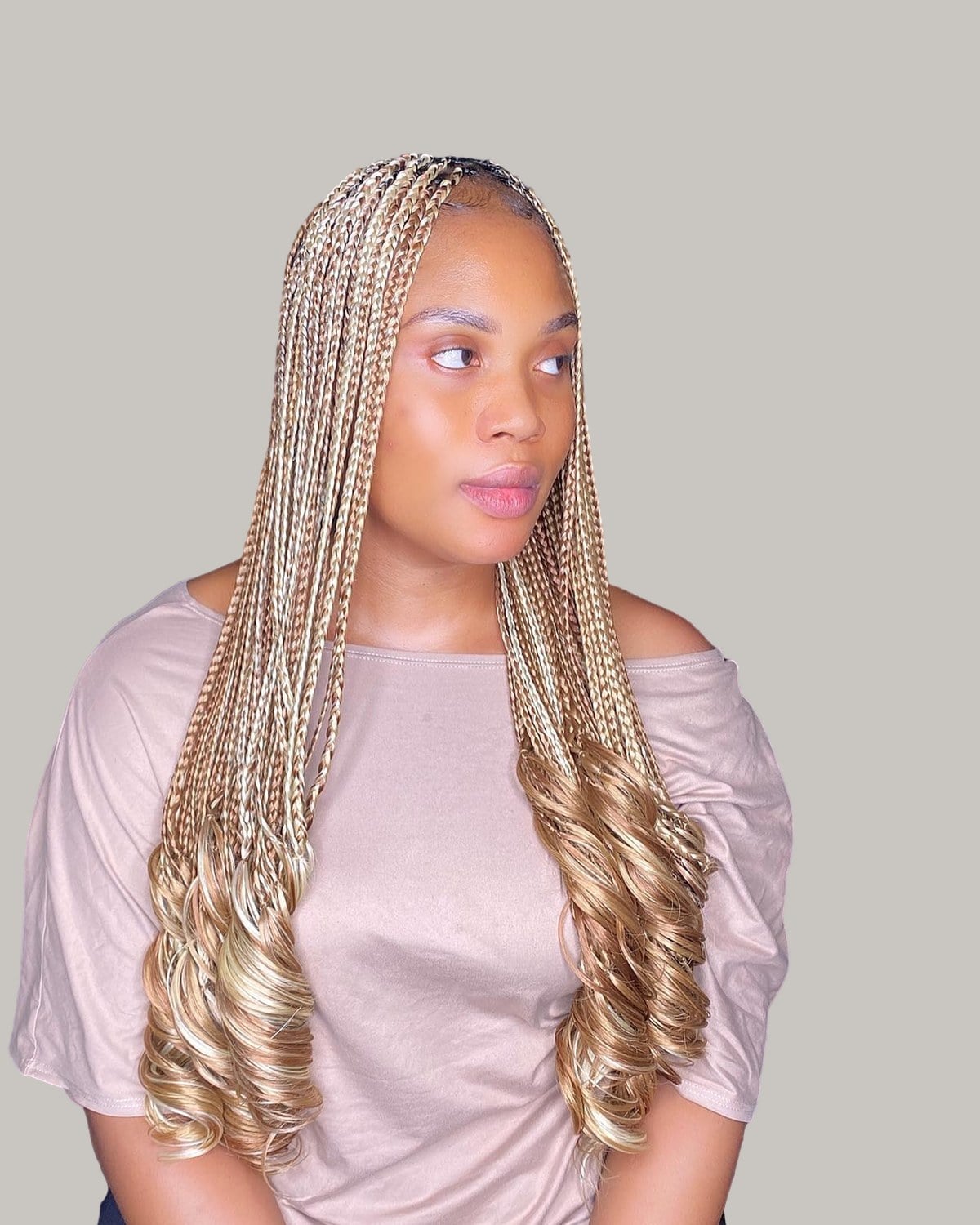 Woman in a pink T-shirt with long honey-blonde French curl braids