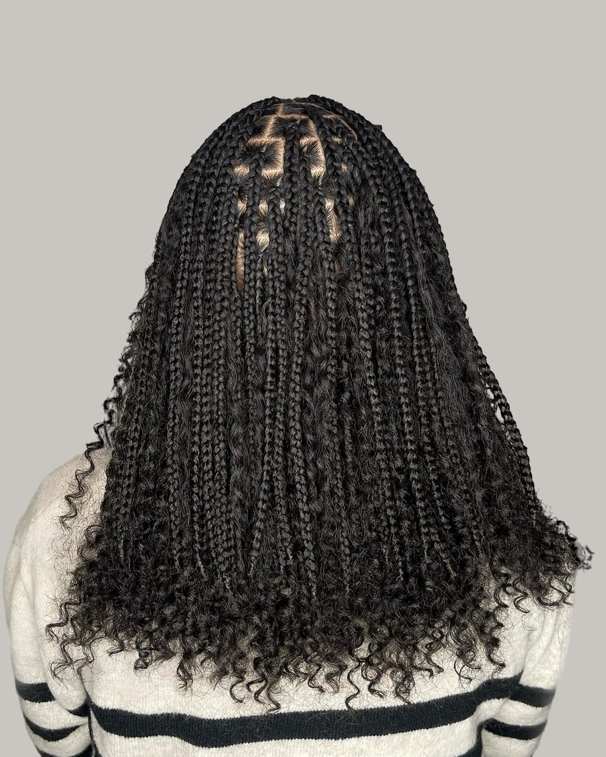 Back view of black boho knotless braids over a striped sweater