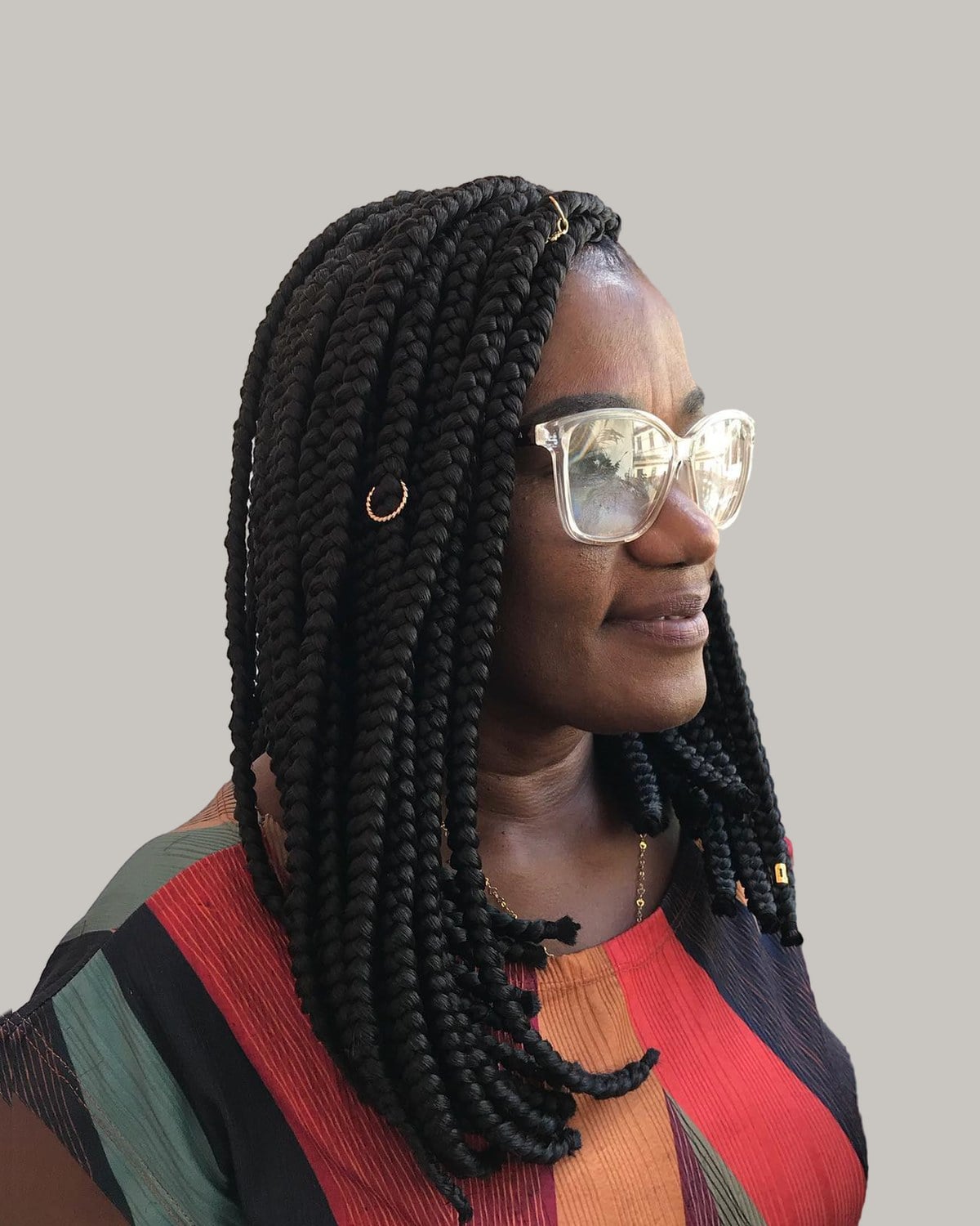 Woman in glasses turned to one side, black box braid bob over a striped top