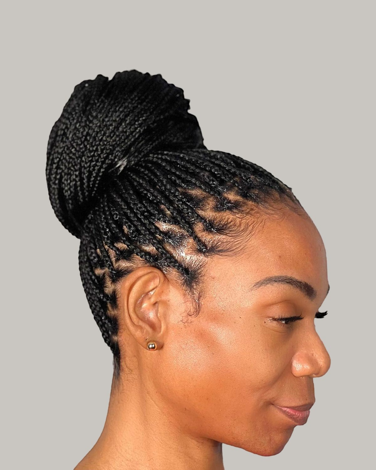 Woman in profile with black box braids in a high top knot