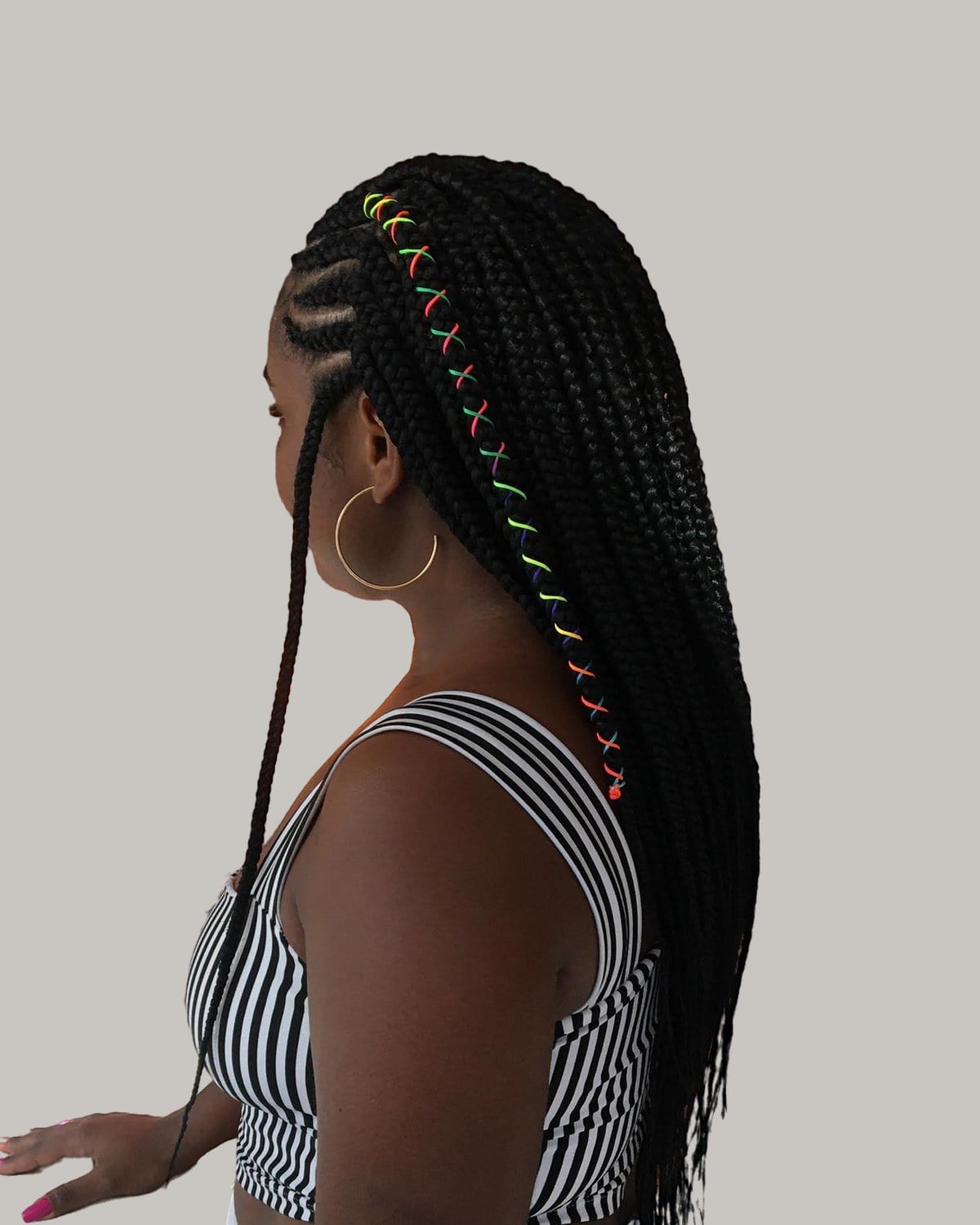 Woman in a striped top in profile, long Fulani braids with colored thread wraps