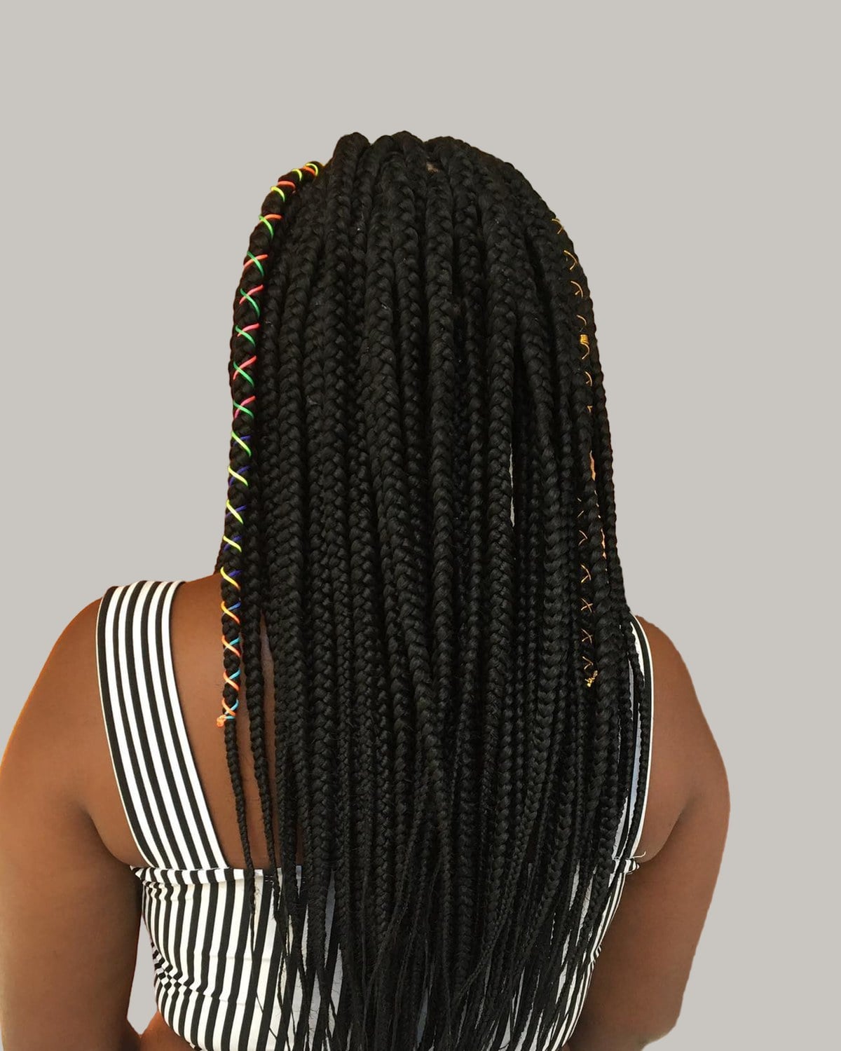 Back view of long Fulani braids with colored thread over a striped top