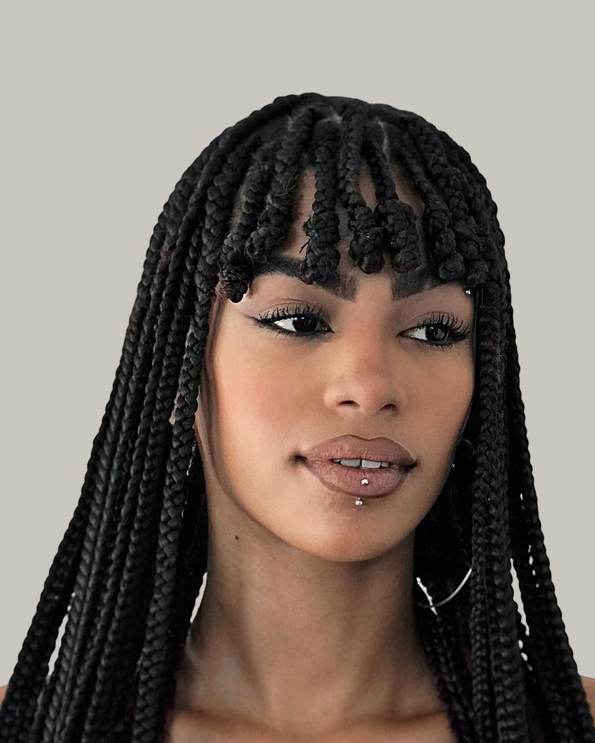 Woman in three-quarter view with jumbo box braids and braided bangs