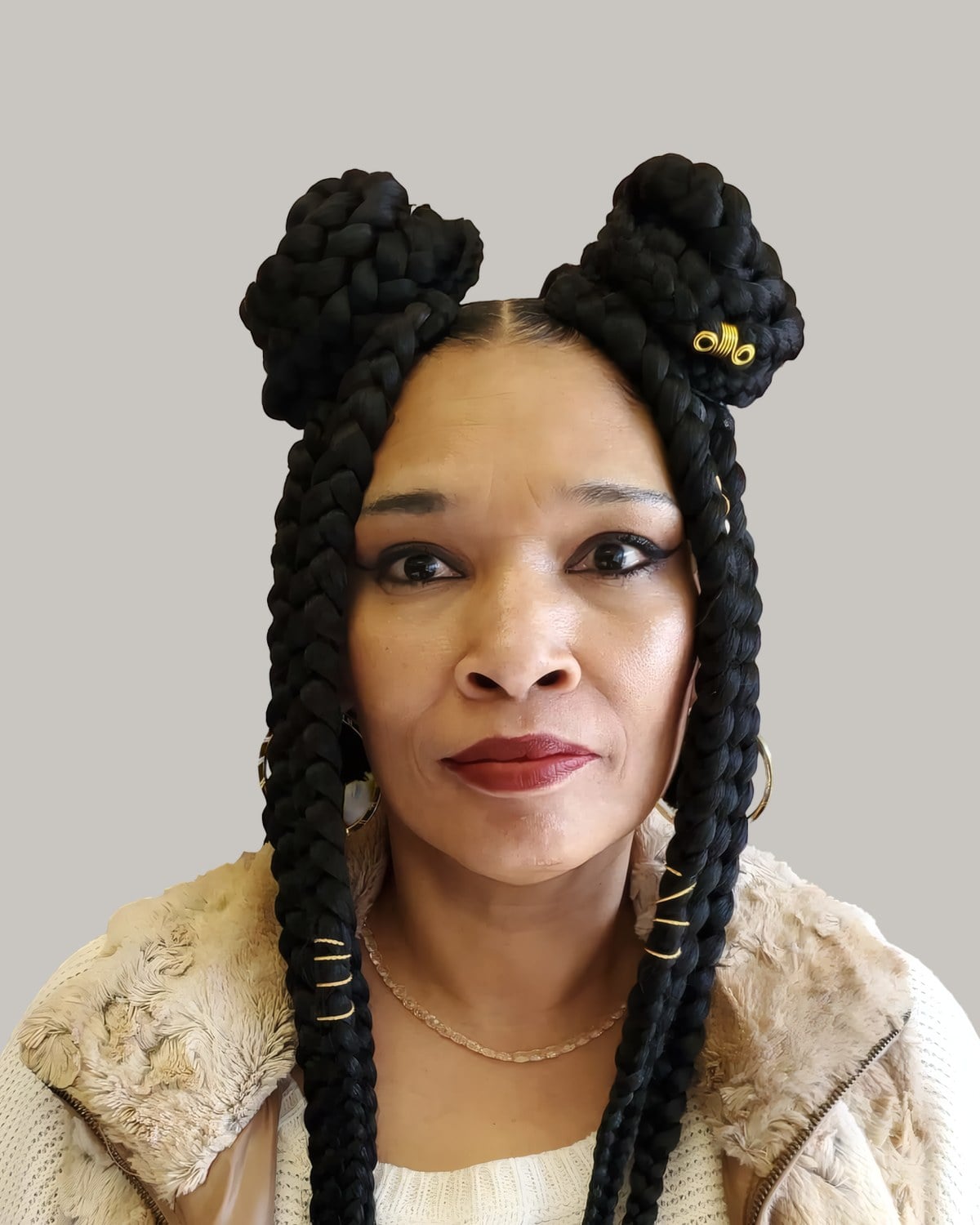 Woman in a cream sweater facing forward with jumbo braid space buns and gold cuffs